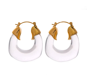 Une paire sur fond blanc de boucles créole de couleur transparente avec à leurs bout un fermoir à bascule en or